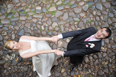 groom and bride in white dress dance on sidewalkの写真素材