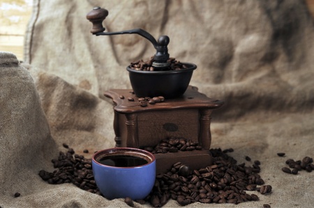 Vintage manual coffee grinder with coffee beans and cupの写真素材