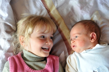 girl with little brother  on parents  bed