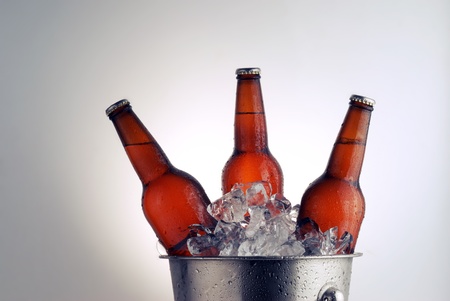 Three brown beer bottles in ice bucket with condensationの写真素材