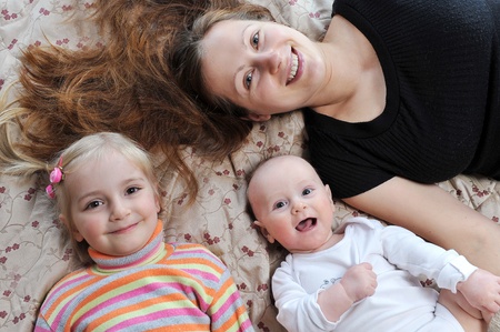Happy mother and her children lying on  bed