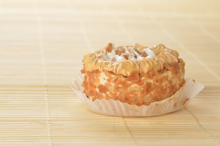 Delicious caramel's  cupcake with white icing on bamboo table cloth