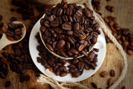Roasted coffee beans with cup on jute hessian backgroundの写真素材