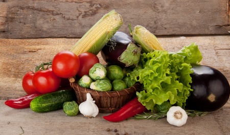 Composition with vegetables in wicker basket on wooden board の写真素材
