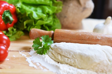 delicious pizza dough, spices and vegetables on wooden table