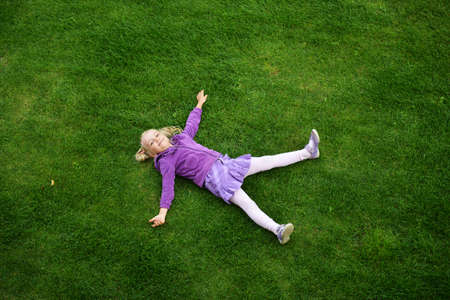 Top view of little girl lying on grass の写真素材