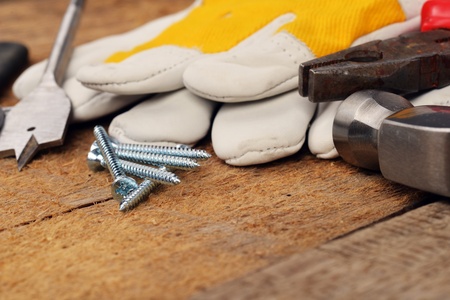 steel screws and different tools on  wooden background.