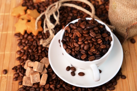 Roasted coffee beans with cup on jute hessian backgroundの写真素材