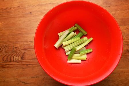 fresh celery sticks in red bowl, closeupの写真素材
