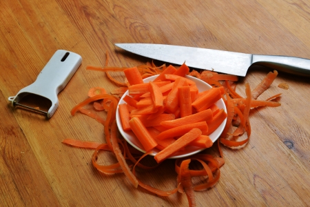 Freshly washed carrots in white dish  and paring knife on wooden backgroundの写真素材