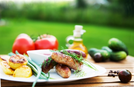 tasty grilled meat sausages  on dish and vegetableの写真素材