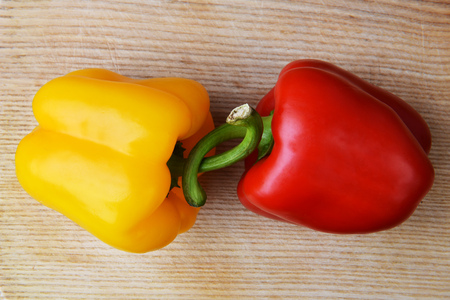 red and  yellow ripe peppers lies on wooden cutting board