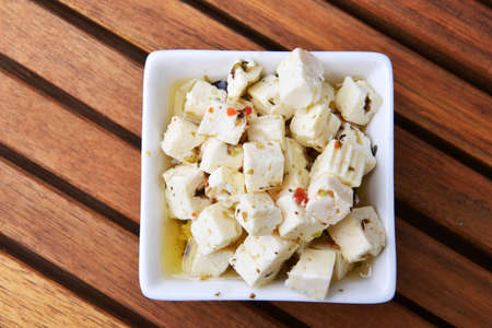 Cubed feta cheese in ceramical bowl on wooden backgroundの写真素材