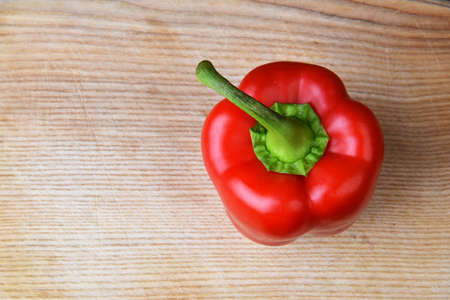 red  ripe pepper lies on wooden cutting boardの写真素材
