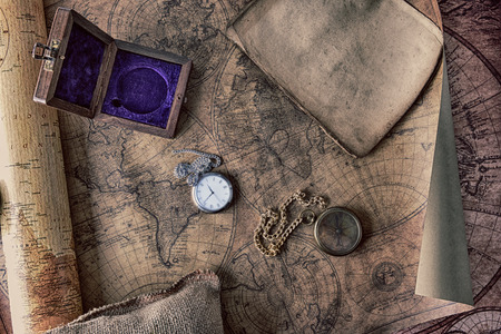 Vintage compass and a pocket watch lying on  old mapの写真素材