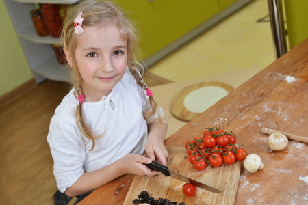 little girl cut vegetables for pizzasの写真素材
