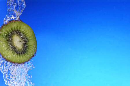 slice of kiwi in the water with bubbles, on blue backgroundの写真素材