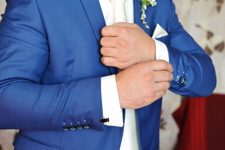 man puts cufflinks on sleeve white shirts