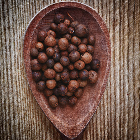 allspice grain in spoon on wooden backgroundの写真素材