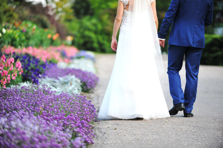 bride and groom walk in park among flowersの写真素材