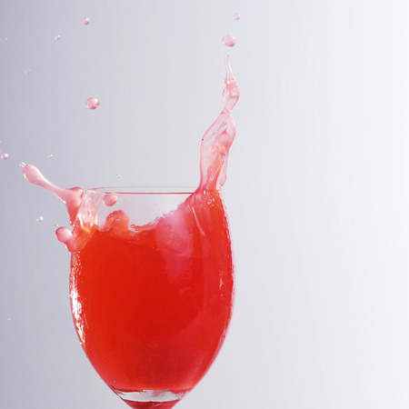 red liquid splashing in glassの写真素材