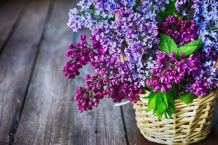 basket with  branch of lilac on wooden backgroundの写真素材
