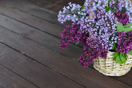 Basket with  branch of lilac on wooden 