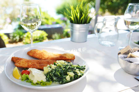 roasted fish, vegetables on dish and glass with wineの写真素材