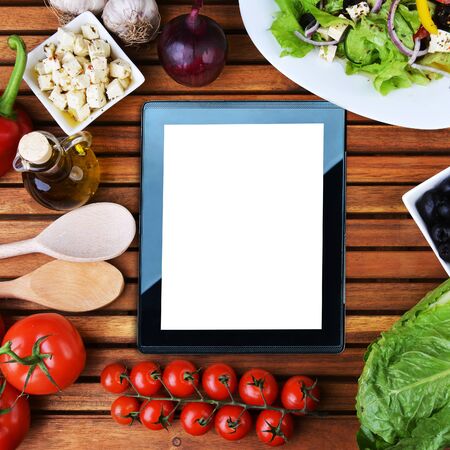tablet , salad with feta cheese and fresh vegetables on wooden backgroundの写真素材
