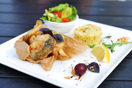 roasted fish, rice and vegetables on dishの写真素材