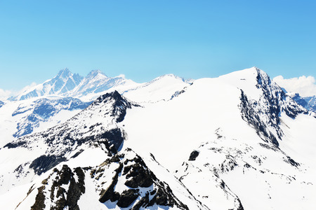 capped mountain peaks and blue skyの写真素材