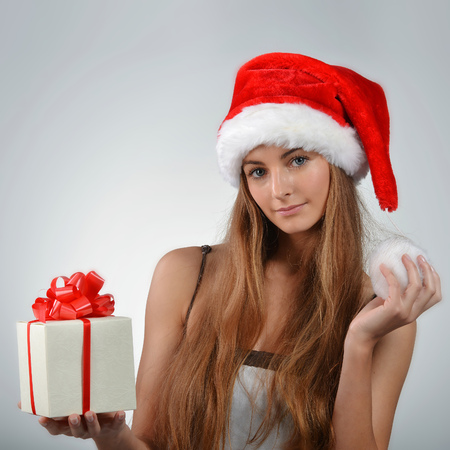 Beautiful young woman in santa claus hat holding gift boxの写真素材