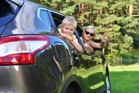 young woman  with her son sit in  modern carの写真素材