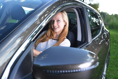 Smiling woman sit in car.car stands on green gladeの写真素材