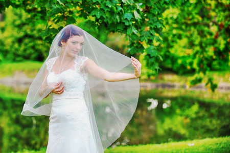 bride in white dress on background of green treesの写真素材