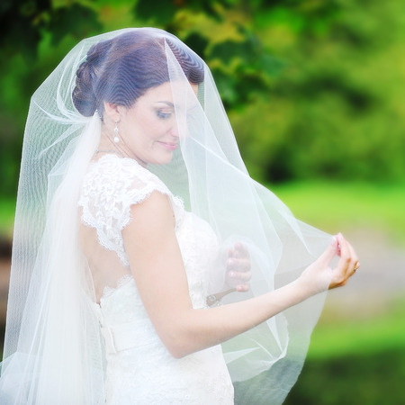 bride in white dress on background of green treesの写真素材