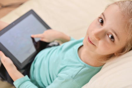 girl using  tablet  sits on couchの写真素材