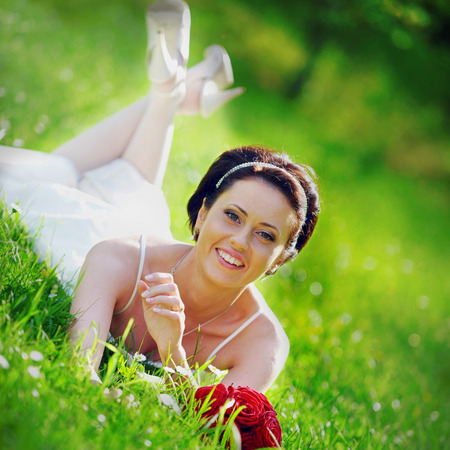 bride in white dress lying down in  grass.の写真素材
