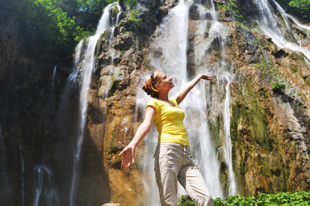 young woman near beautiful waterfalls on slopes of mountainsの写真素材