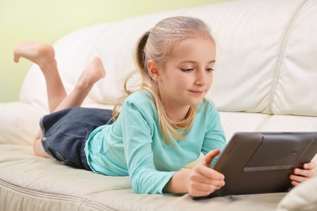 girl with modern tablet lying on sofaの写真素材