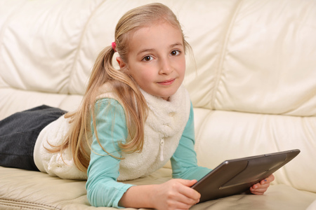 girl with modern tablet lying on sofaの写真素材