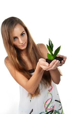Beautiful young woman with green sprout of tree in her palmsの写真素材