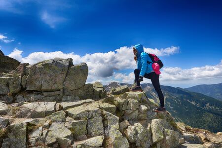 young woman in mountains, background of sky and cloudsの写真素材