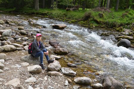 young woman on mountains slopes near creekの写真素材