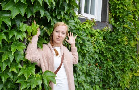 woman on sidewalk alongside  green ivyの写真素材