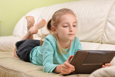 girl with modern tablet lying on sofaの写真素材