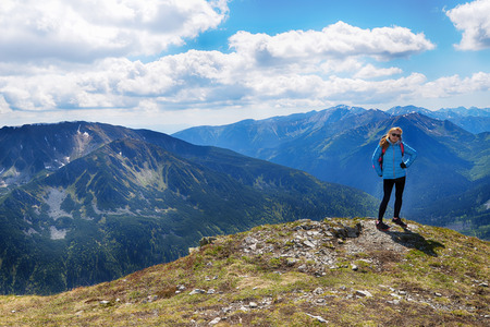young woman in mountains, background of sky and cloudsの写真素材