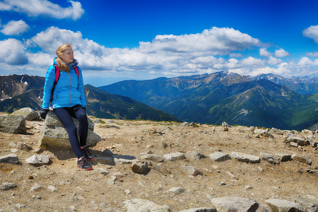 young woman in mountains, background of sky and cloudsの写真素材