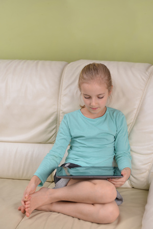 girl using  tablet  sits on couchの写真素材