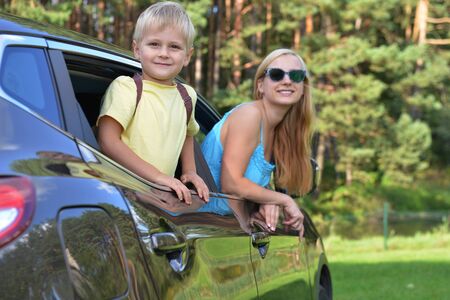 young woman  with her children sit in  modern carの写真素材